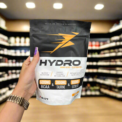 Close-up of BLDR Sports Hydro 360g) held up inside My Supplement Shop, clearly showing the front label in a Sports Nutrition setting.