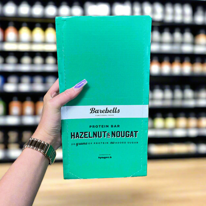 Close-up of (Barebells Protein Bars 12x55g) held up inside My Supplement Shop, clearly showing the front label in a Sports Nutrition setting.