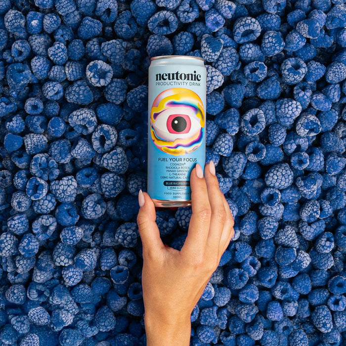 Neutriku can held by a hand over blue raspberries