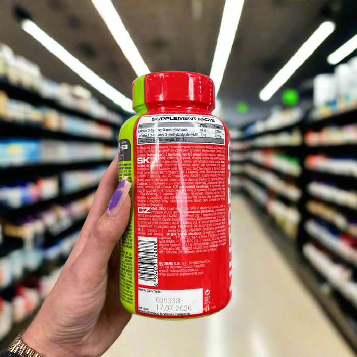 Close-up of (Nutrend HMB 4500 - 100 caps) held up inside My Supplement Shop, clearly showing Nutritional Values on the packaging in a Sports Nutrition setting.