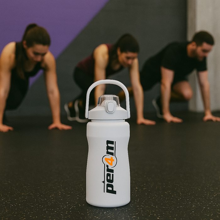 White Per4m water bottle in sharp focus on a gym floor with people performing HIIT training in the blurred background