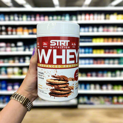 Close-up of (STRT Nutrition Whey Protein 500g) held up inside My Supplement Shop, clearly showing the front label in a Sports Nutrition setting.