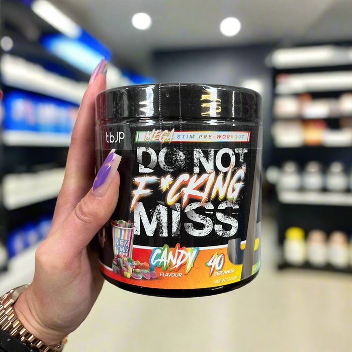 Close-up of Trained By JP DNFM New Pre Workout 320g) held up inside My Supplement Shop, clearly showing the front label in a Sports Nutrition setting.